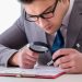 Businessman with magnifying glass studying agreement